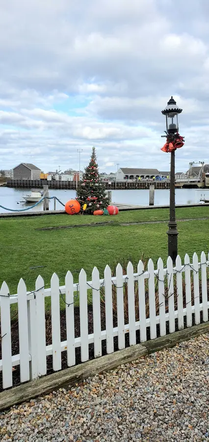 The buoy tree behind a white picket fence by the harbor