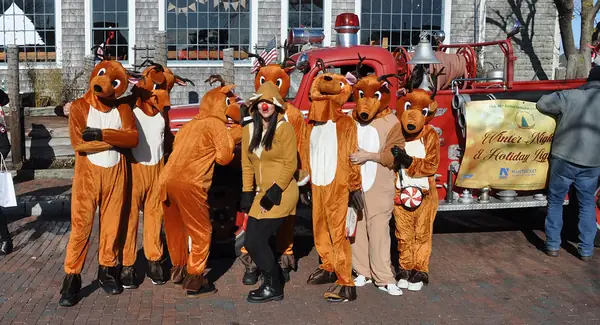 A group in reindeer costumes beside an antique fire truck