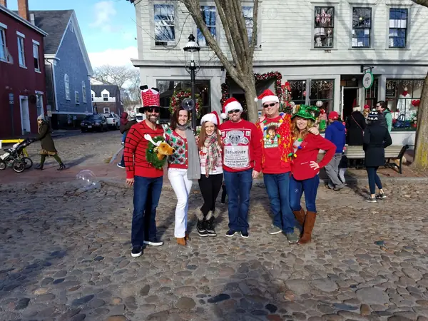 Friends in holiday sweaters and Santa hats on the cobblestones