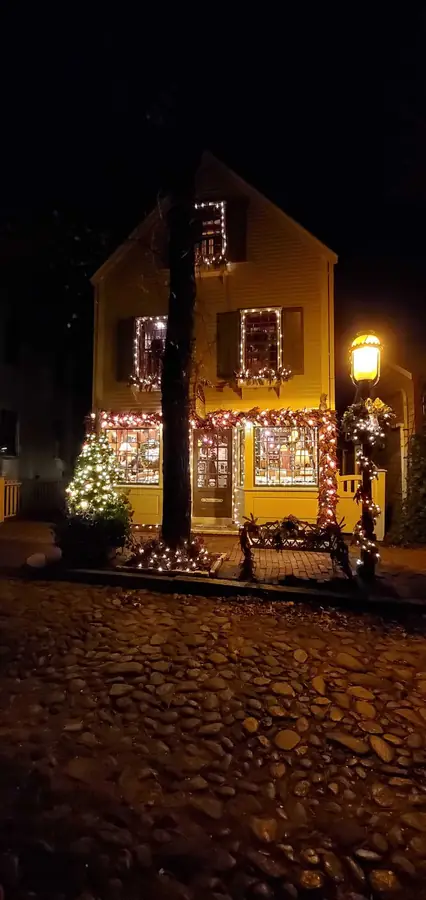 Yellow shop trimmed with holiday lights on a cobblestone street